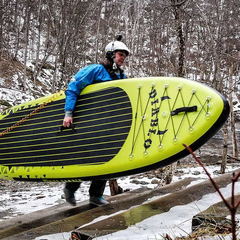 Pau Hana Surf Supply Diablo Air whitewater inflatable paddleboard being carried up snowy staircase wearing whitewater safety equipment and drysuit