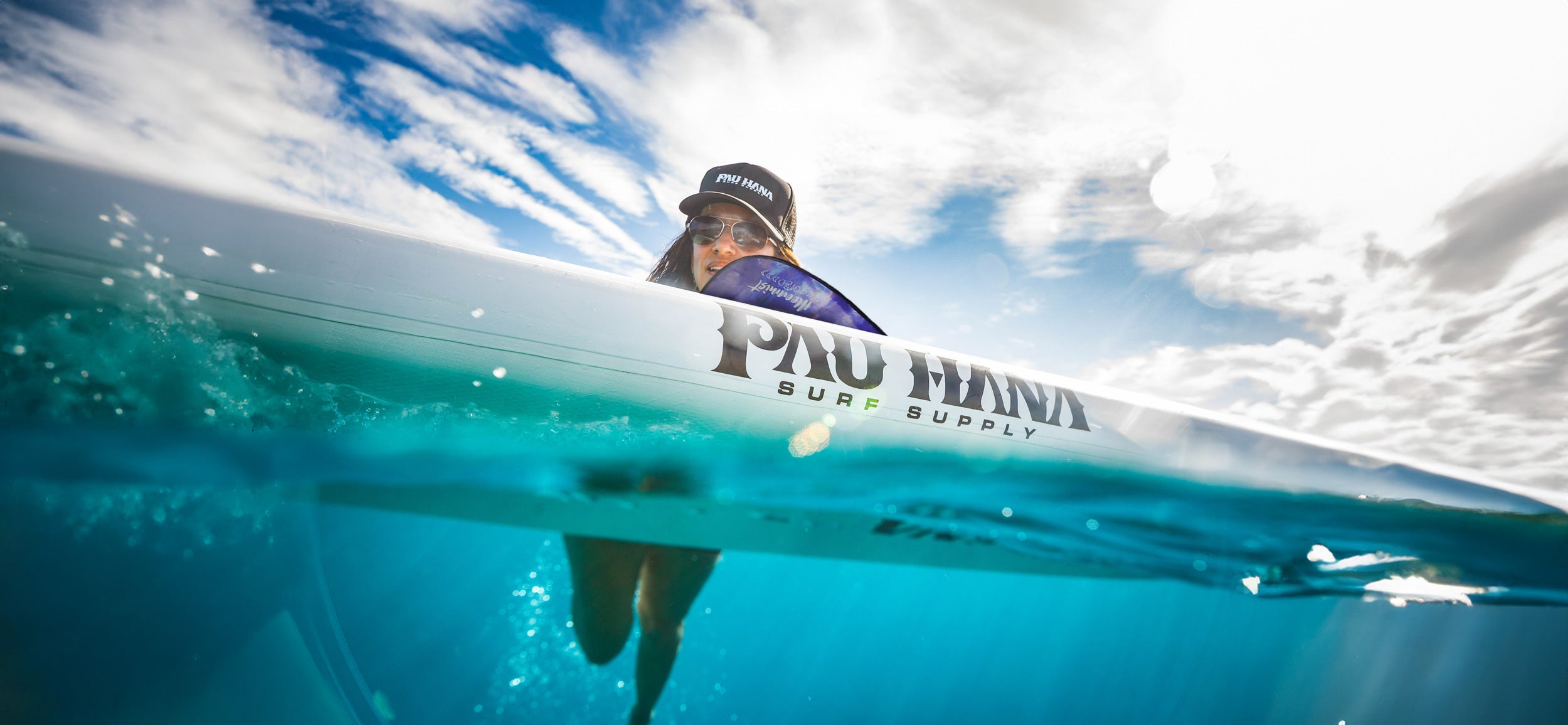 A woman swimming next to the Pau Hana Big EZ Air inflatable paddleboard