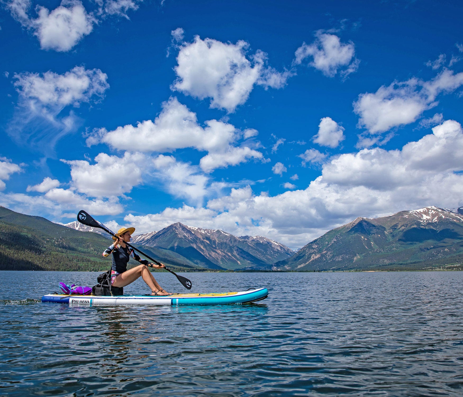 Person paddleboarding on a lake with mountains in the background