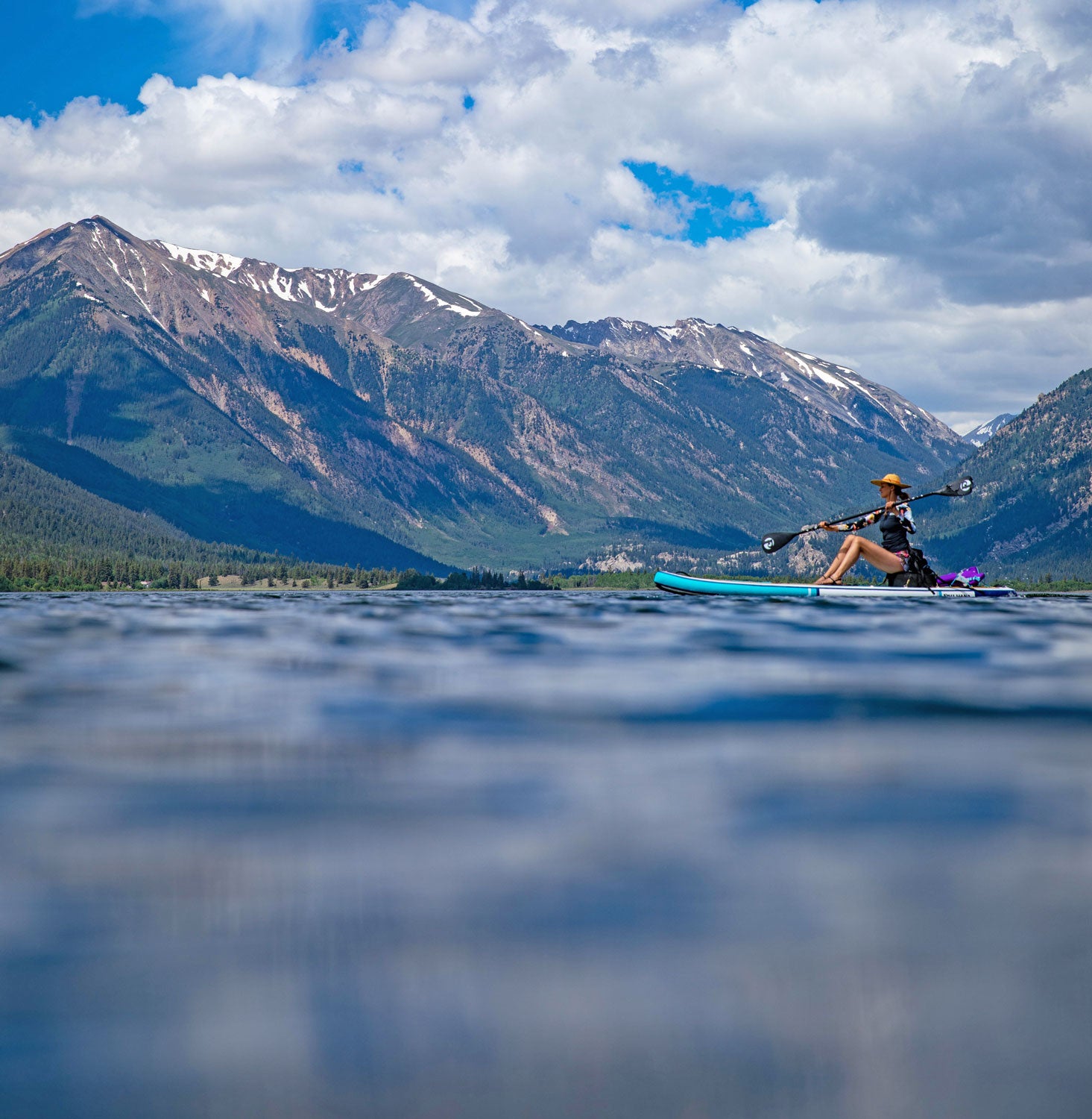 Person paddleboarding on an alpine lake with mountains in the background