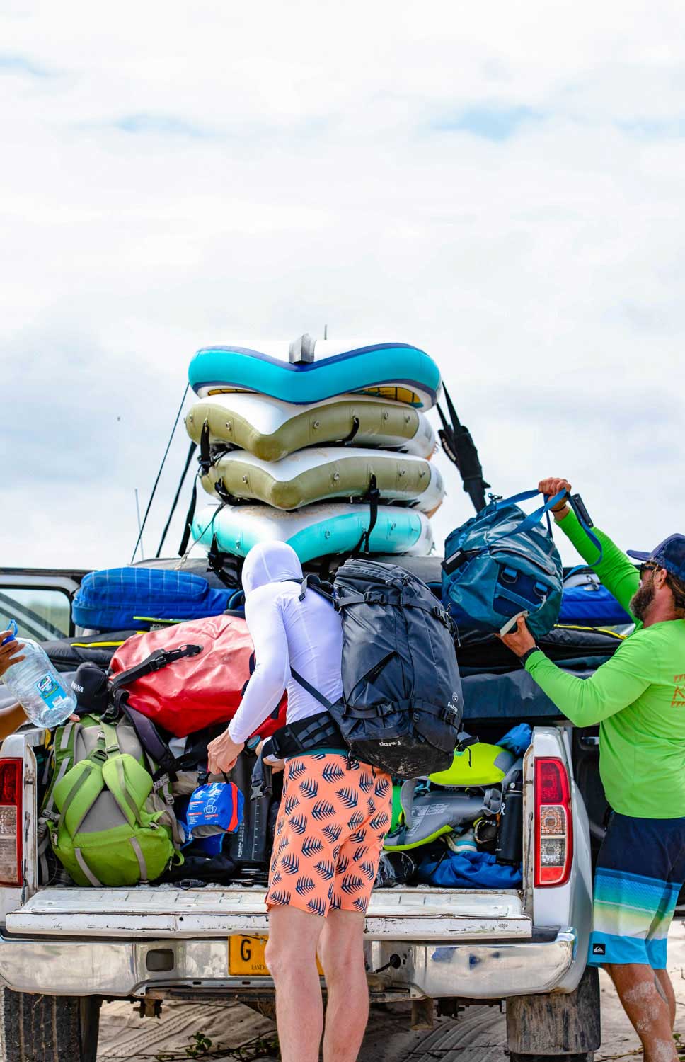 two guys loading up a truck with inflatable paddleboards and gear for a big trip