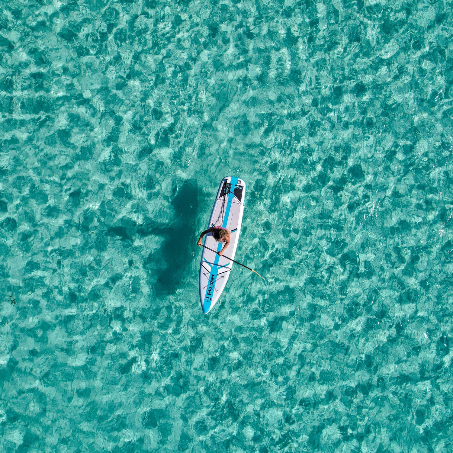 a person paddleboarding over clear waters in the ocean