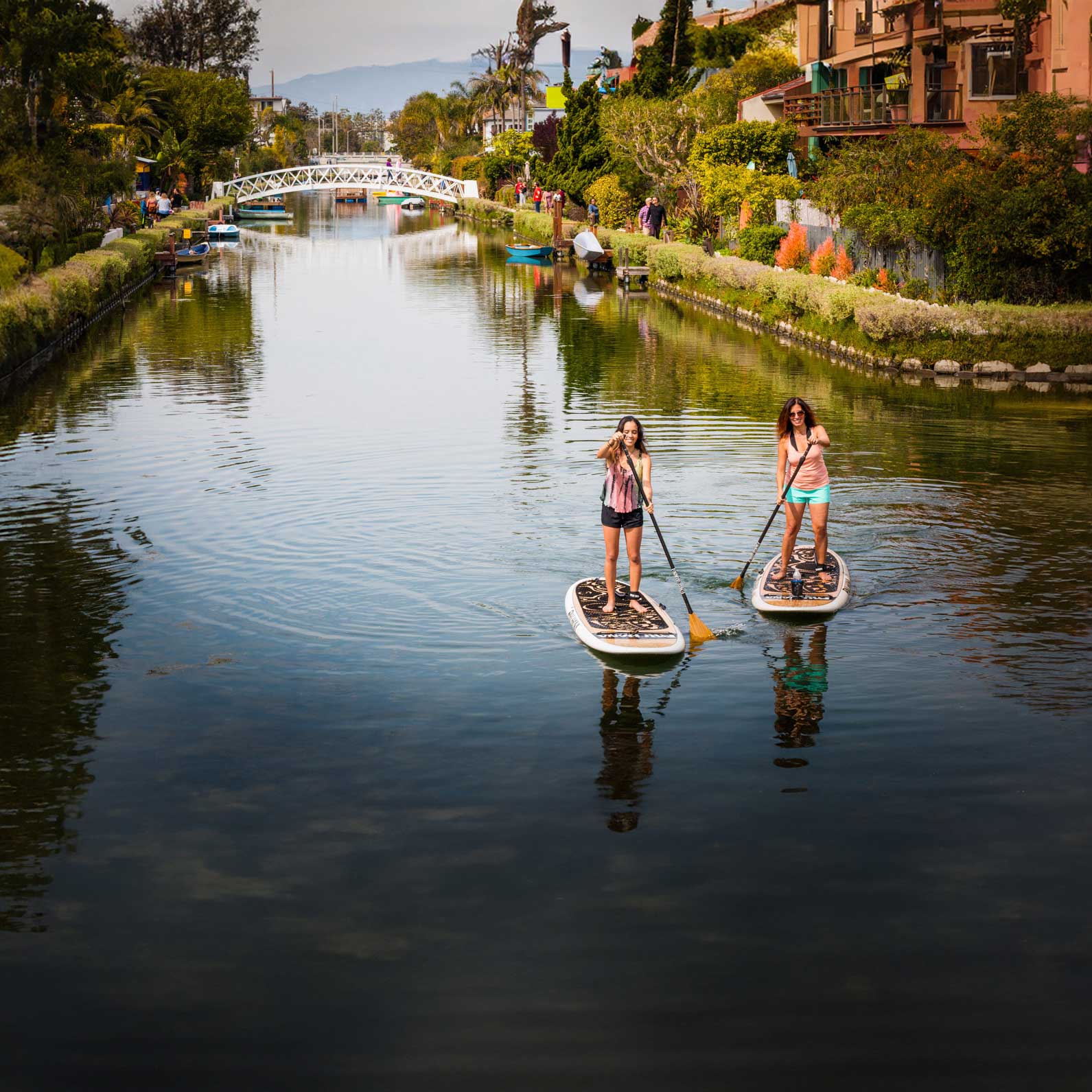 two people paddling the pau hana oahu paddleboard on the venice canals in los angeles california