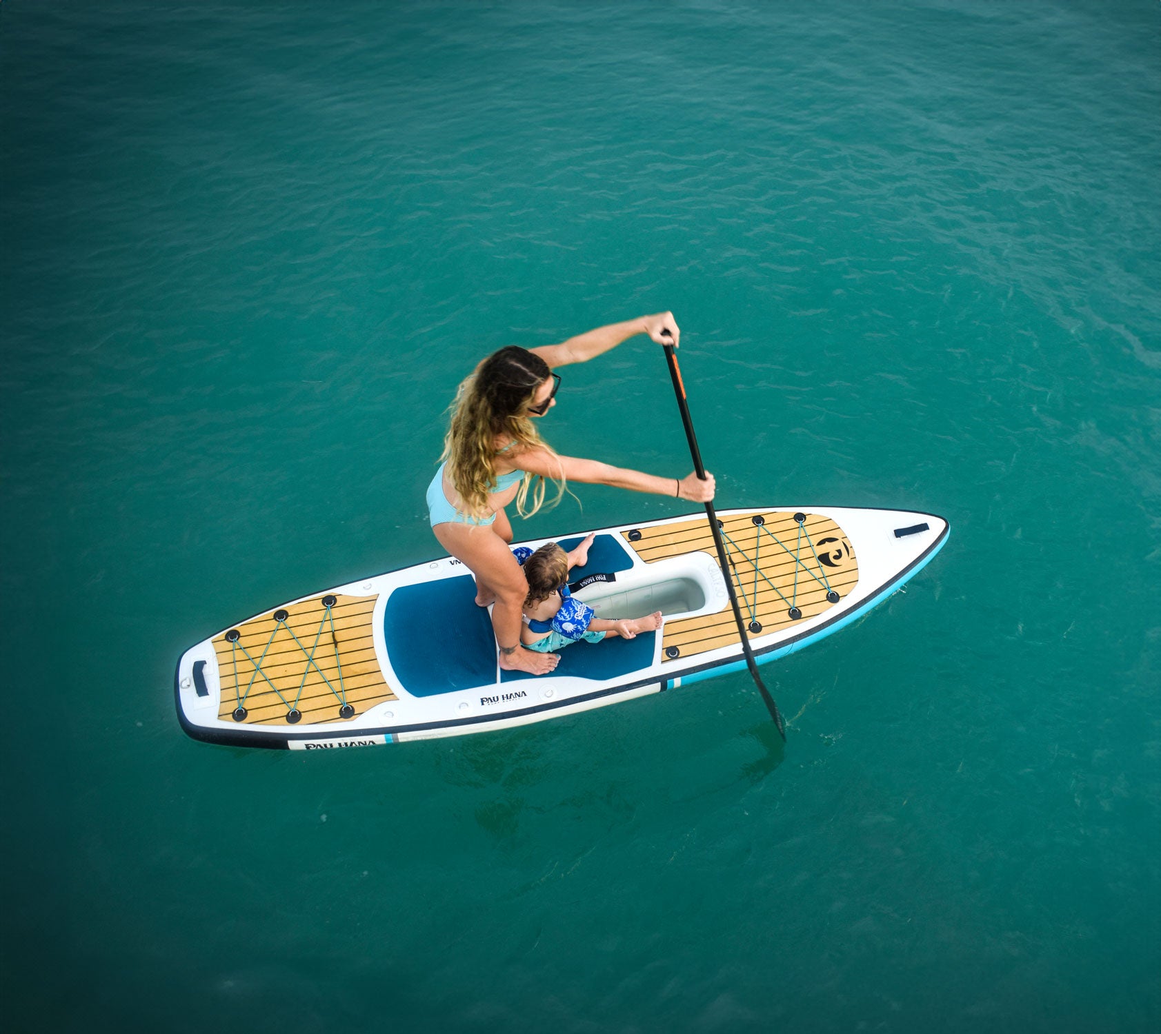 Person paddleboarding on a clear blue water surface