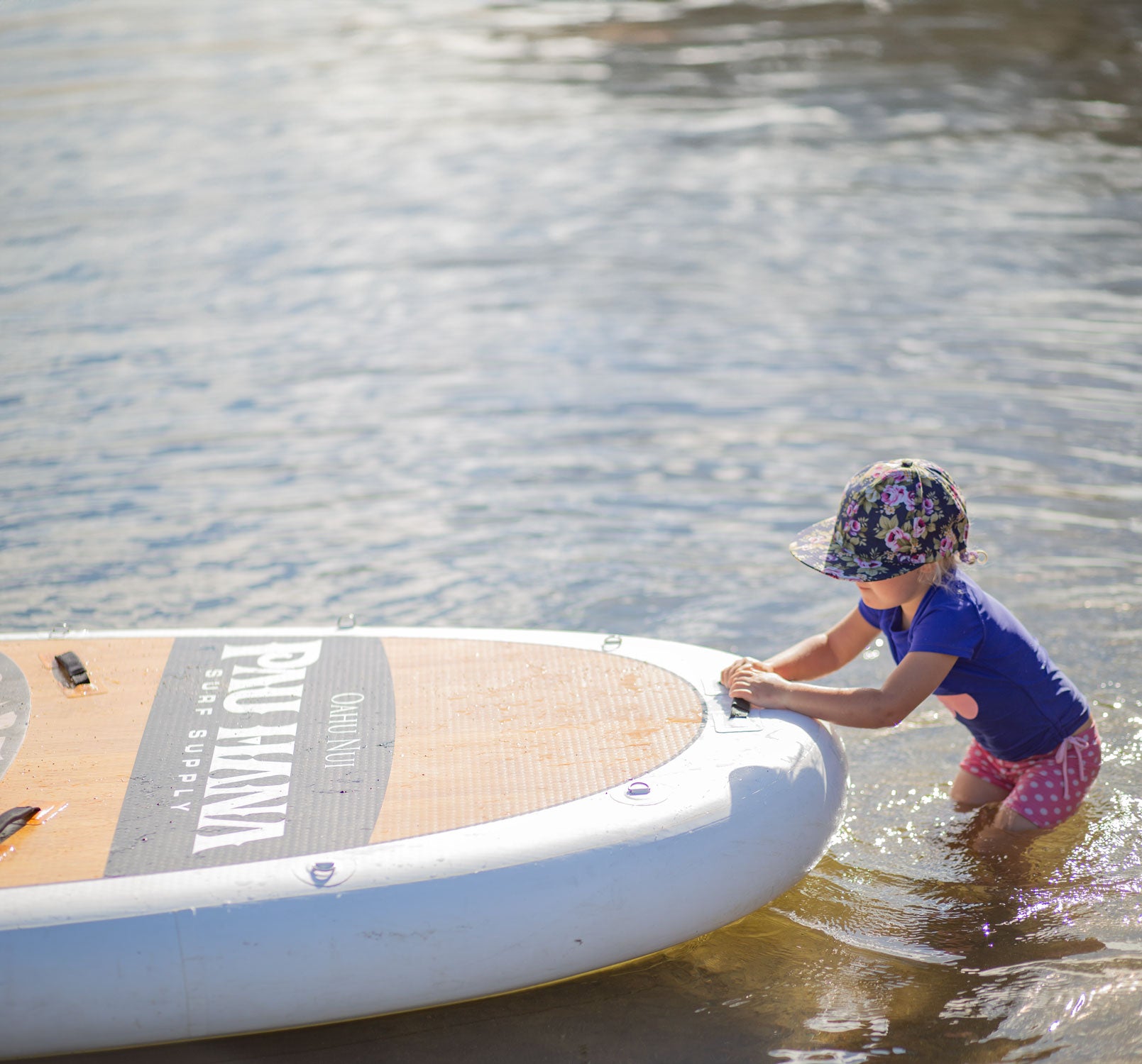 a child holding onto the Oahu Nui giant SUP on a lake