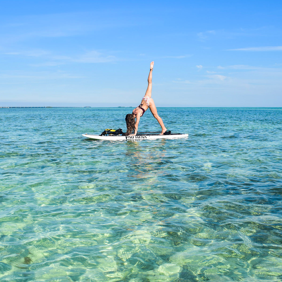 a person doing yoga on a paddleboard in the ocean with clear water