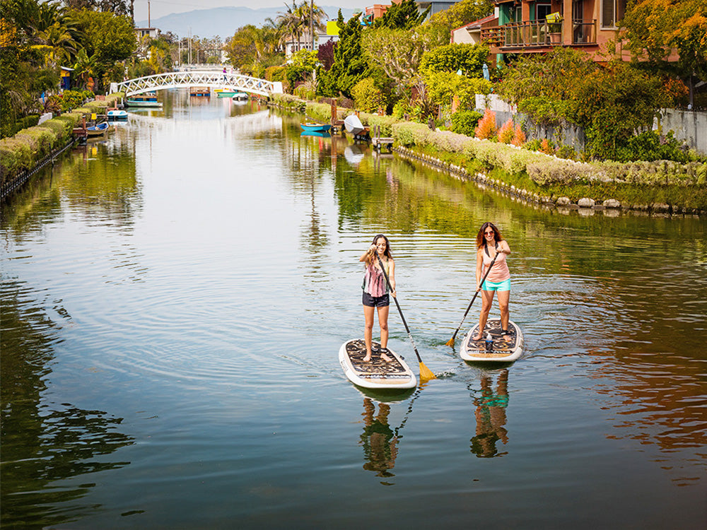 two people paddling paddlebaords on the venice canals in California
