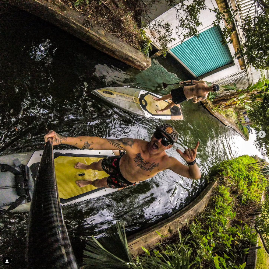 "Pau Hana Surf Supply Endurance touring SUP board in action on narrow waterway, showing maneuverability in tight spaces"