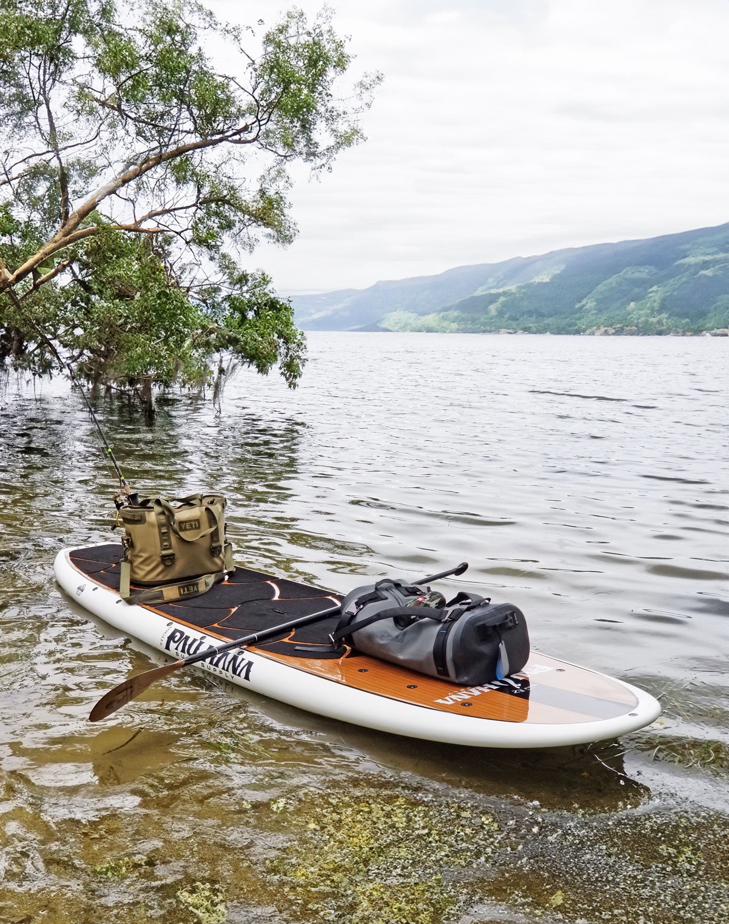 A fishing paddleboard on a lake with trees in the background