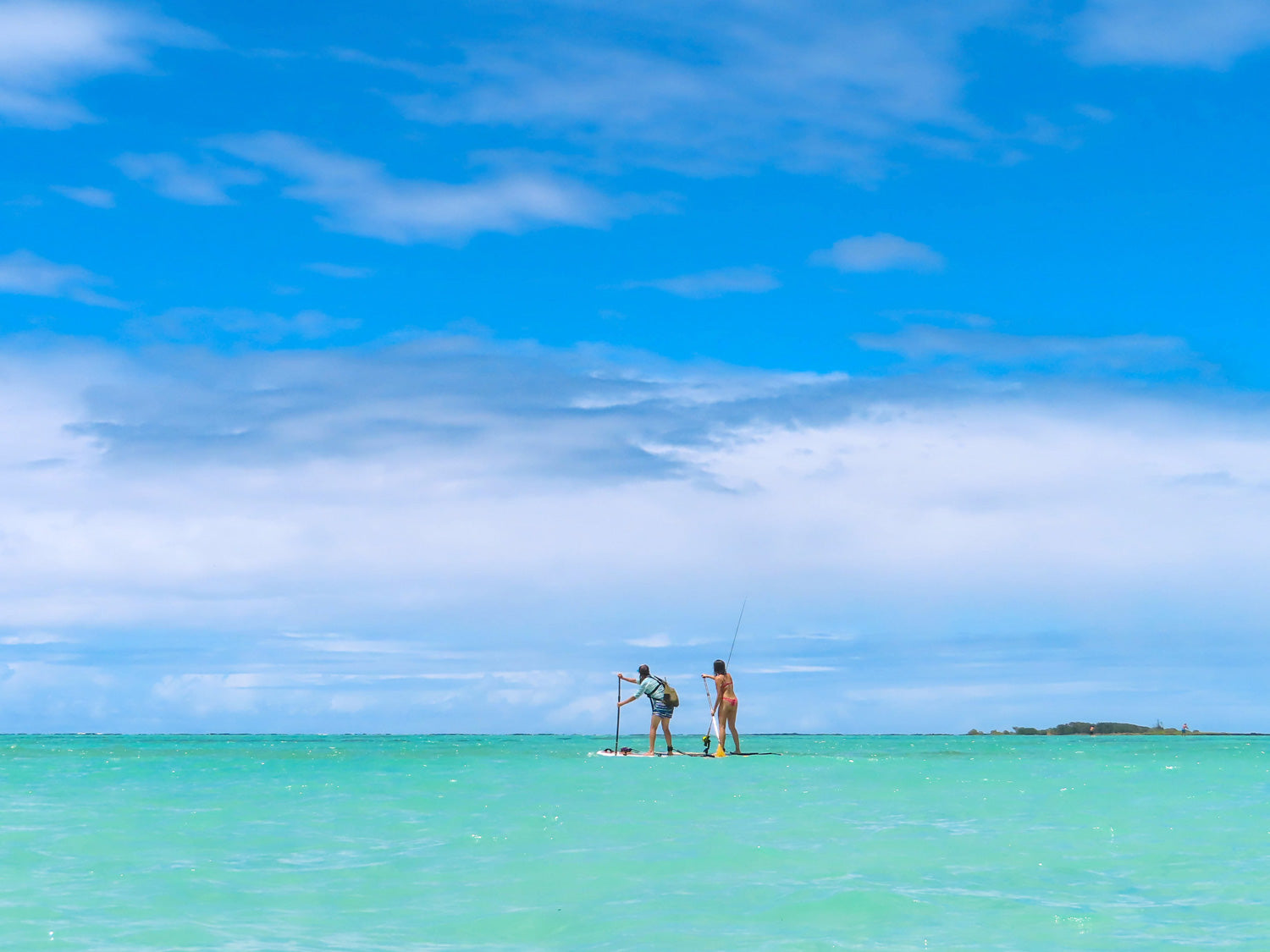 Two paddleboarders on Pau Hana Surf Supply Navio VFT and Big EZ VFT boards using Carbon Teak paddles in turquoise Hawaiian waters