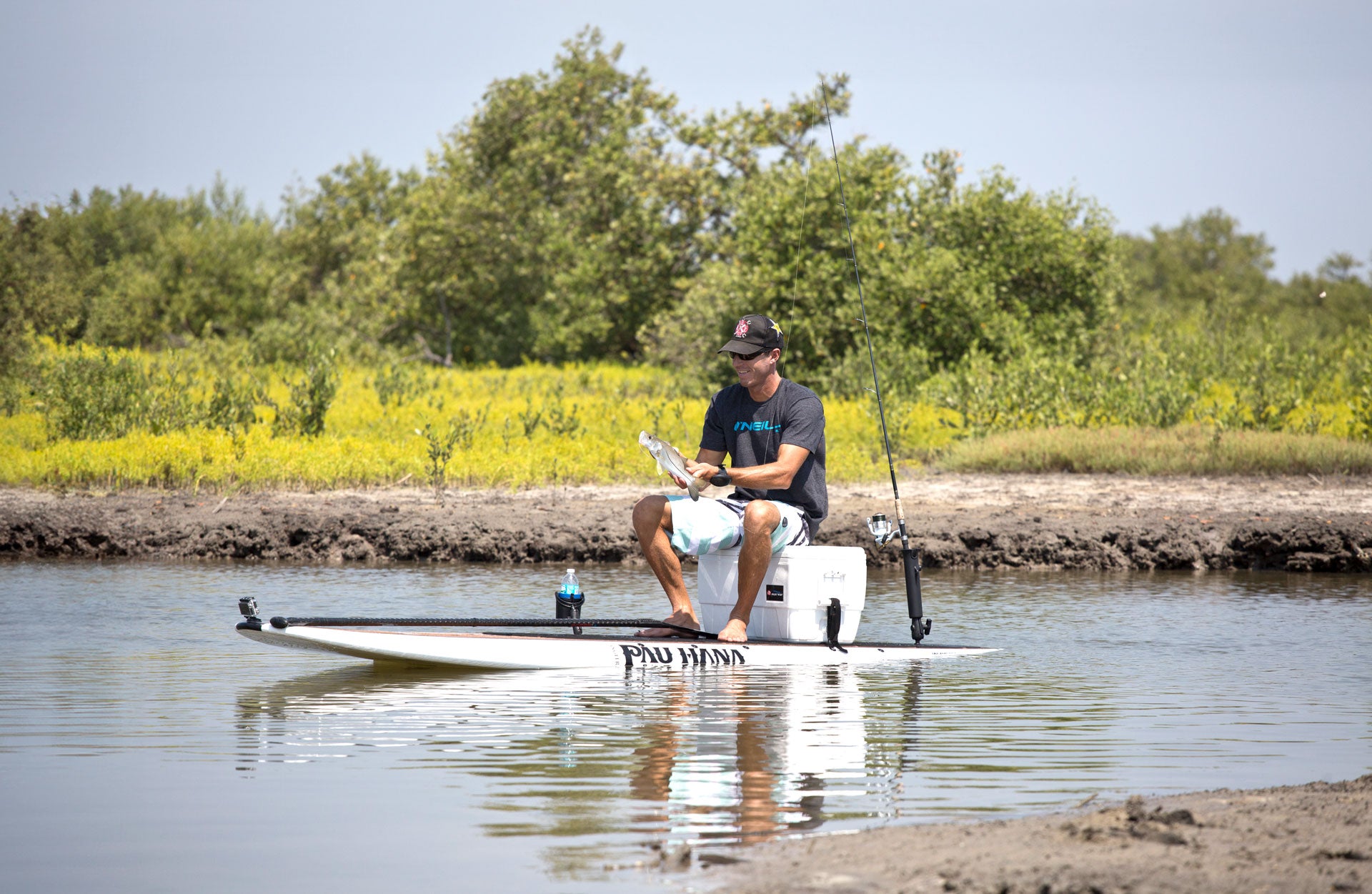 "Successful snook catch displayed on Pau Hana Surf Supply Angler fishing SUP, showcasing comfort deck pad, cooler and tackle in Florida mangroves"