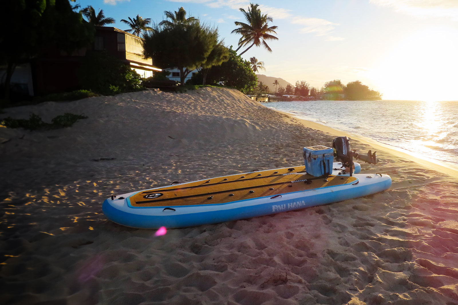 Pau Hana Surf Supply Bimini inflatable skiff with motor on a beach in Oahu at sunset