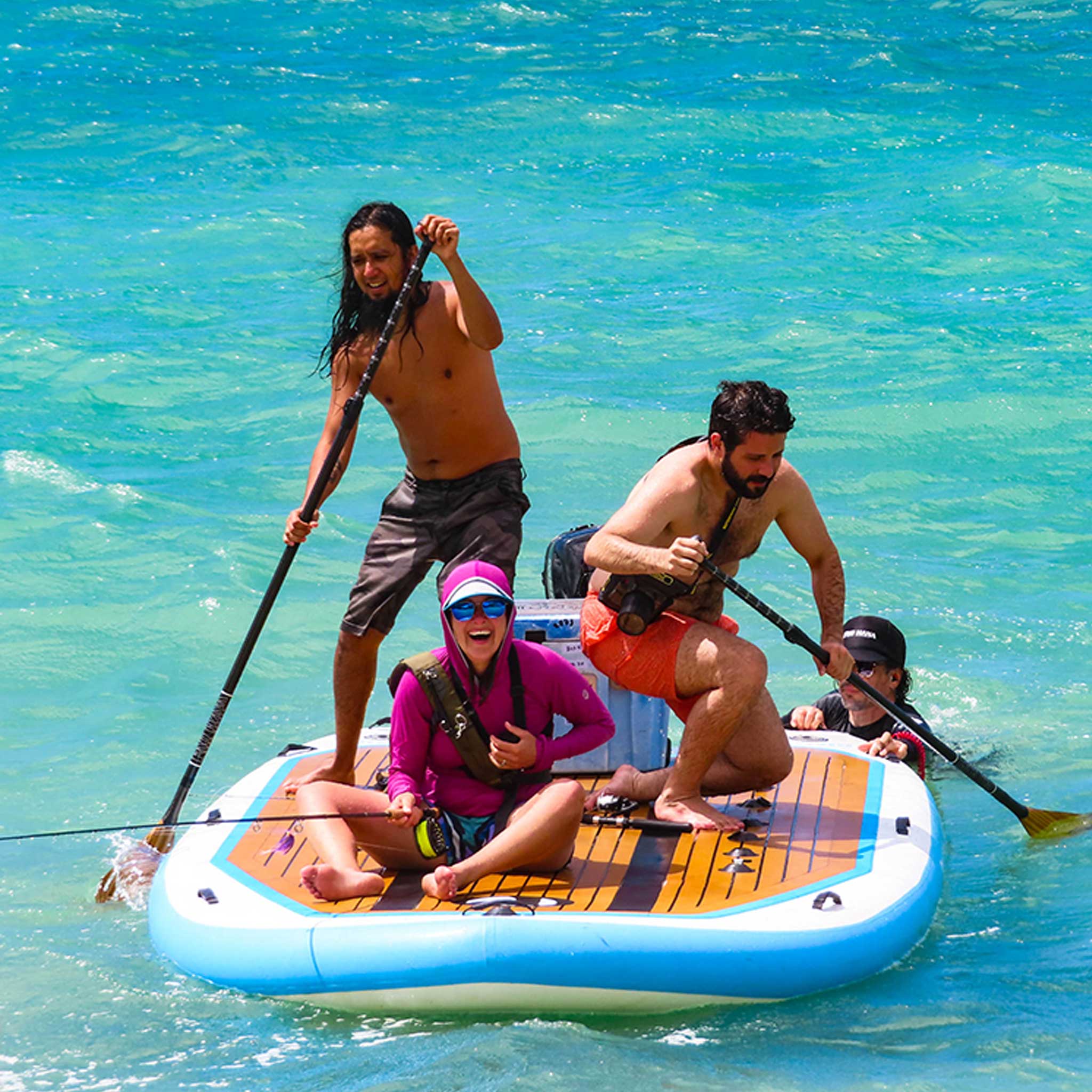 "Pau Hana Surf Supply Bimini Skiff inflatable SUP with motor, people enjoying turquoise Hawaiian waters, showcasing party-style paddleboarding capacity"