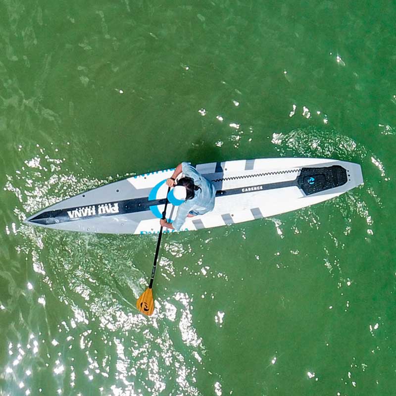 "Aerial image of paddler on Pau Hana Surf Supply Cadence race and fitness SUP showcasing maneuverability and tracking with a carbon teak paddle"