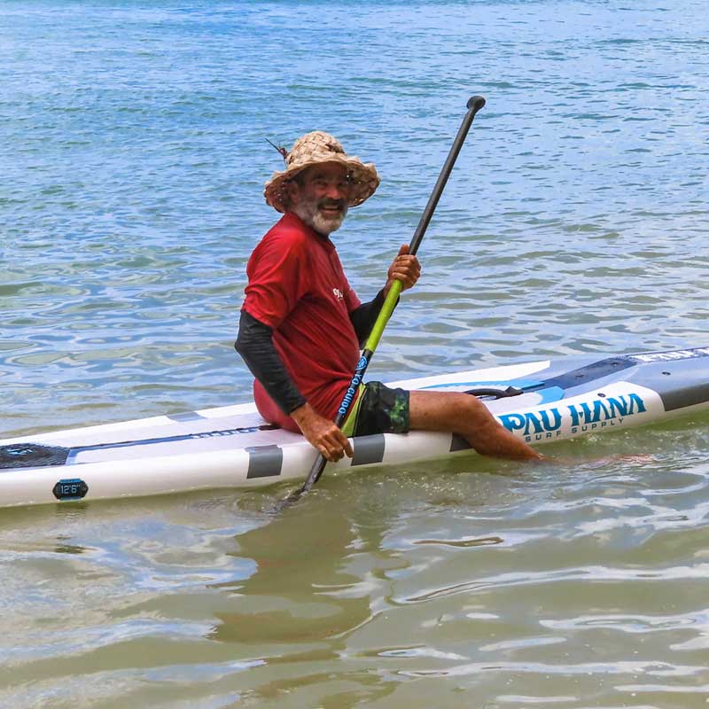 "Pau Hana Surf Supply 12'6" Cadence high performance race and fitness SUP, paddler takes break on calm waters"