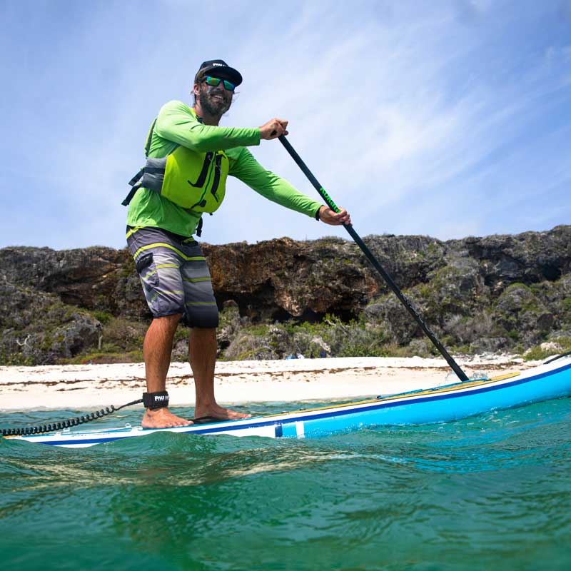 &quot;Paddler with life jacket and leash on Pau Hana Surf Supply Calypso keel hull kayak and SUP close to beach&quot;