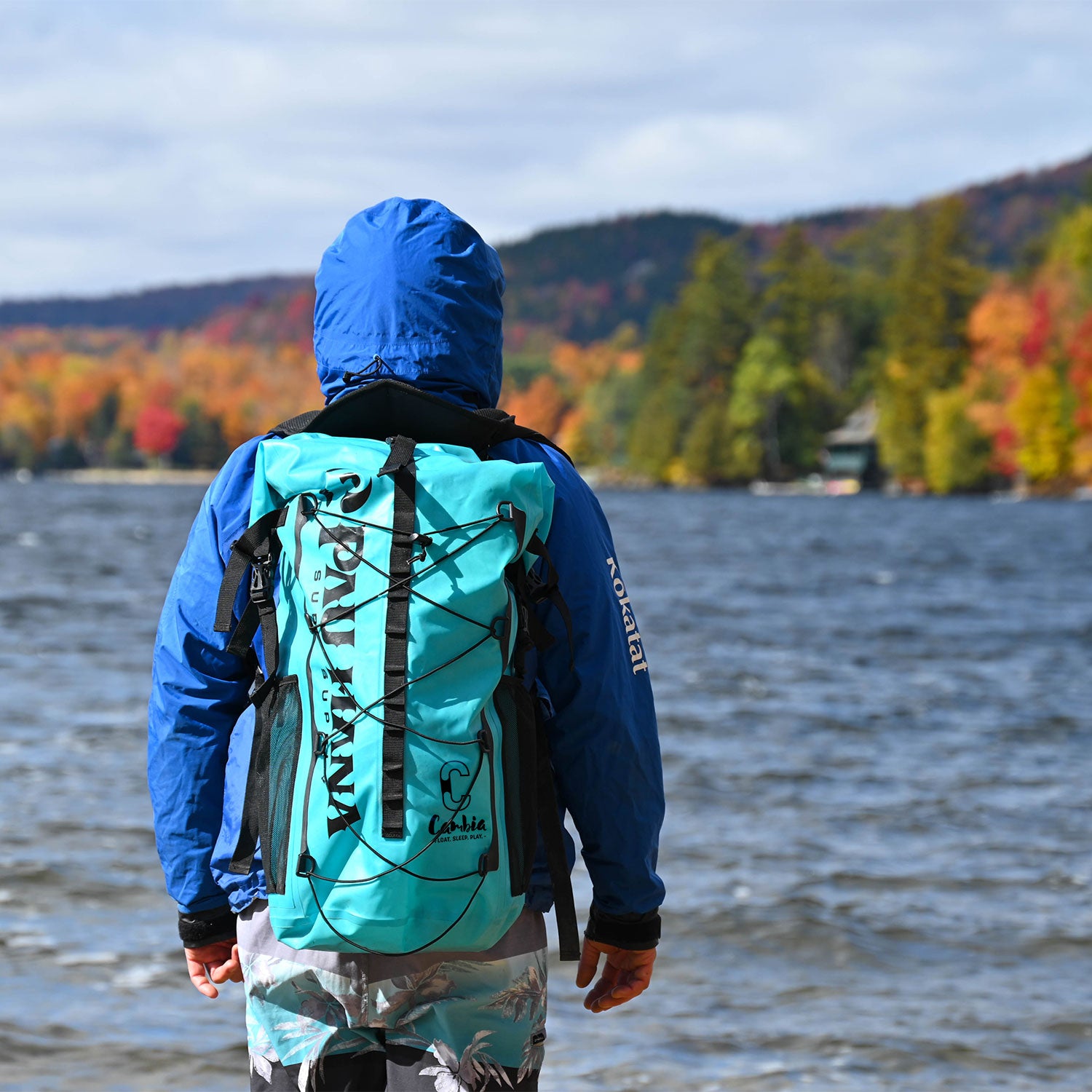 A man standing by a lake with the Pau Hana Surf Supply Cambia backpack on looking out over the water