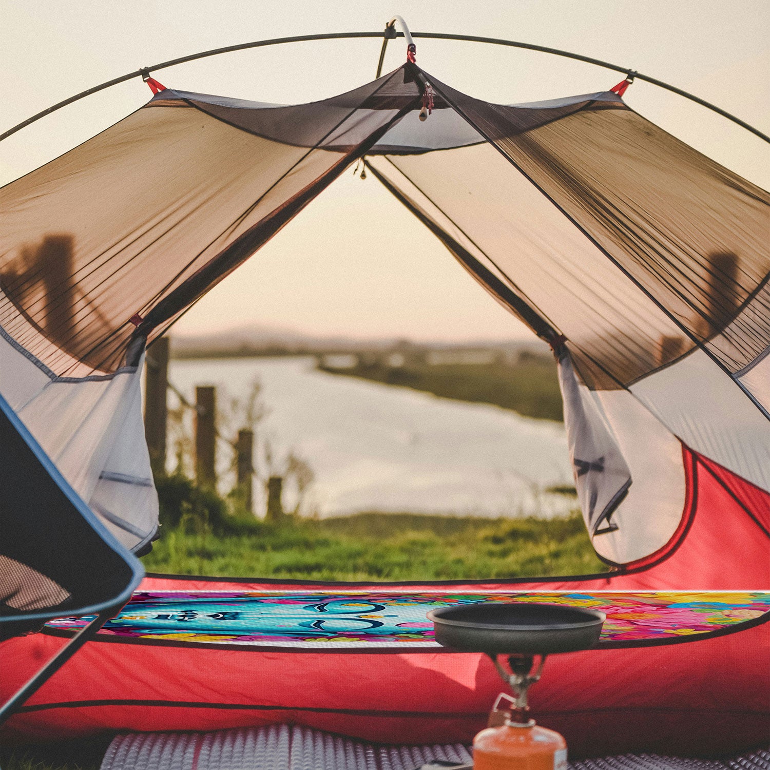 View inside a tent of the Pau Hana Surf Supply Cambia Power of Flower design being used as a mattress with a view of a lake in the background