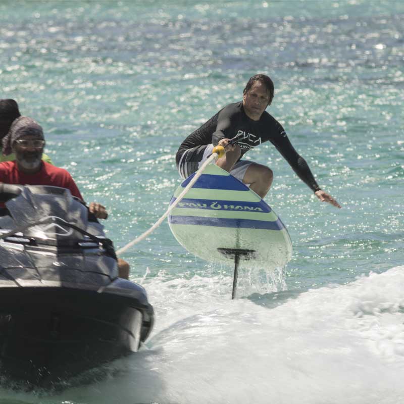 "Pau Hana Surf Supply Carve Surf SUP hydrofoiling being towed by a jetski