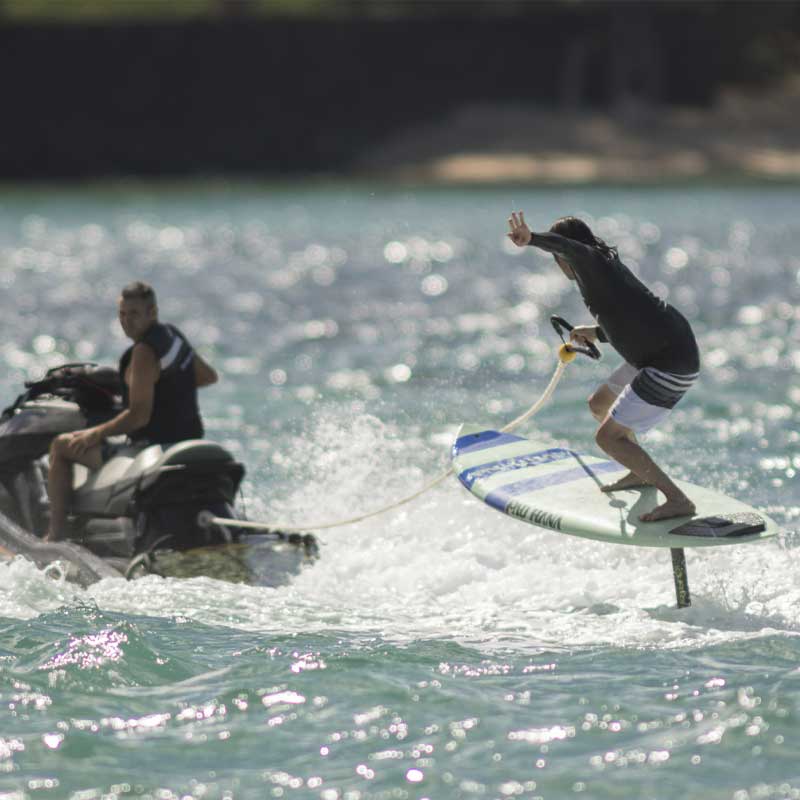 "Pau Hana Surf Supply Carve Surf SUP hydrofoiling being towed by a jetski"