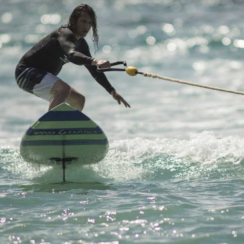 "Pau Hana Surf Supply Carve Surf SUP hydrofoiling being towed by a jetski"