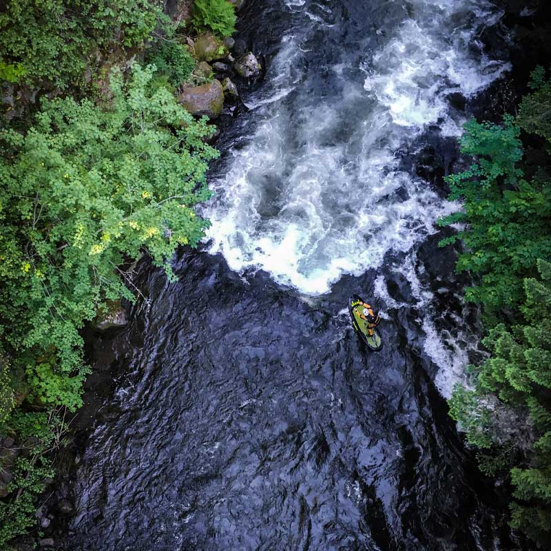 Aerial image of Pau  Hana Surf Supply Diablo whitewater paddleboard running whitewater rapids in a river