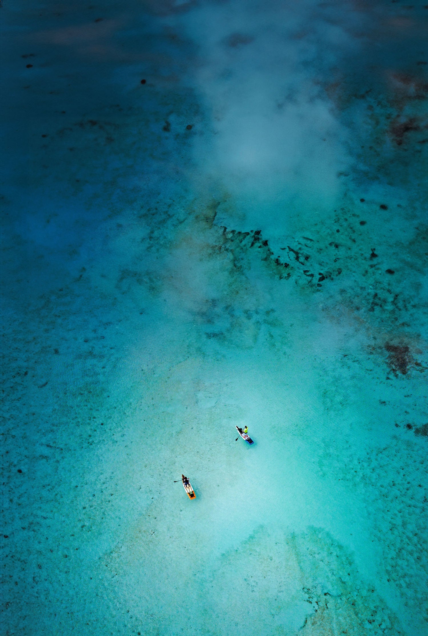 "Aerial view of two paddlers on Pau Hana Surf Supply Endurance Air touring SUPs exploring Caribbean turquoise waters and coral reefs during island adventure"