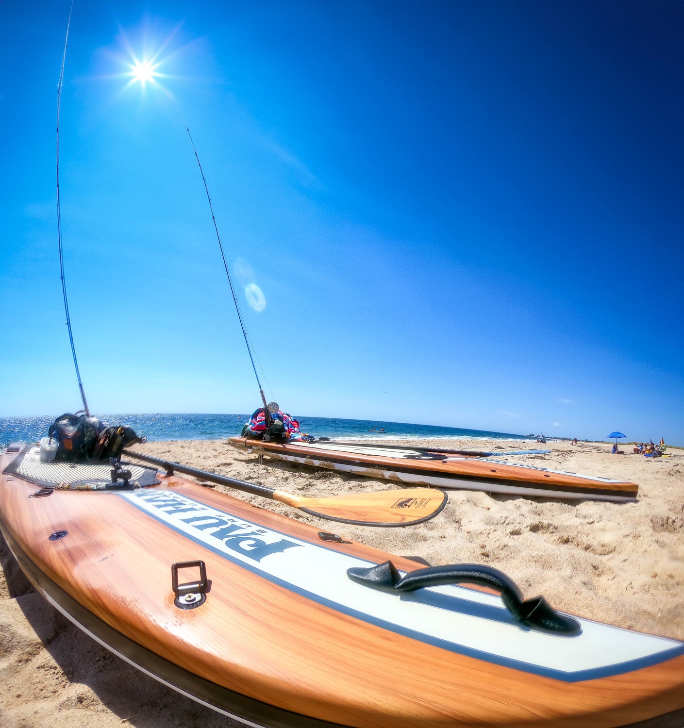 Close up image of the Pau Hana Surf Supply Endurance VFT paddleboards set up with fly rods on the beach