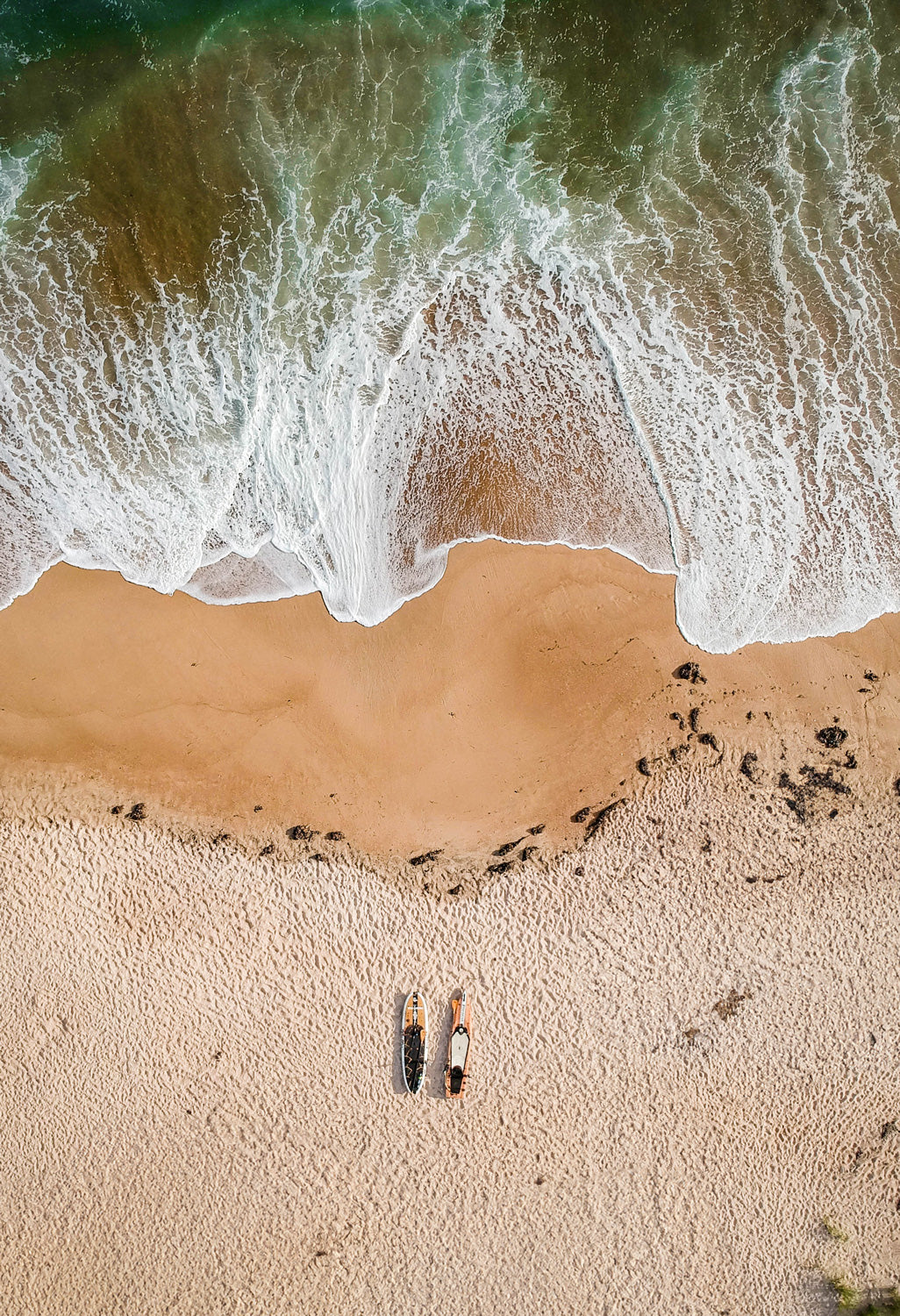 Aerial view the Pau Hana Surf Supply Endurance VFT touring board and Big EZ Angler fishing SUP resting on rippled sand beach