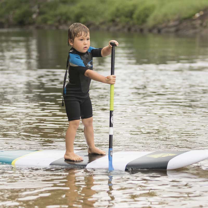 "Young paddler learning SUP technique on Pau Hana Surf Supply Grom X kids board with adjustable youth paddle"