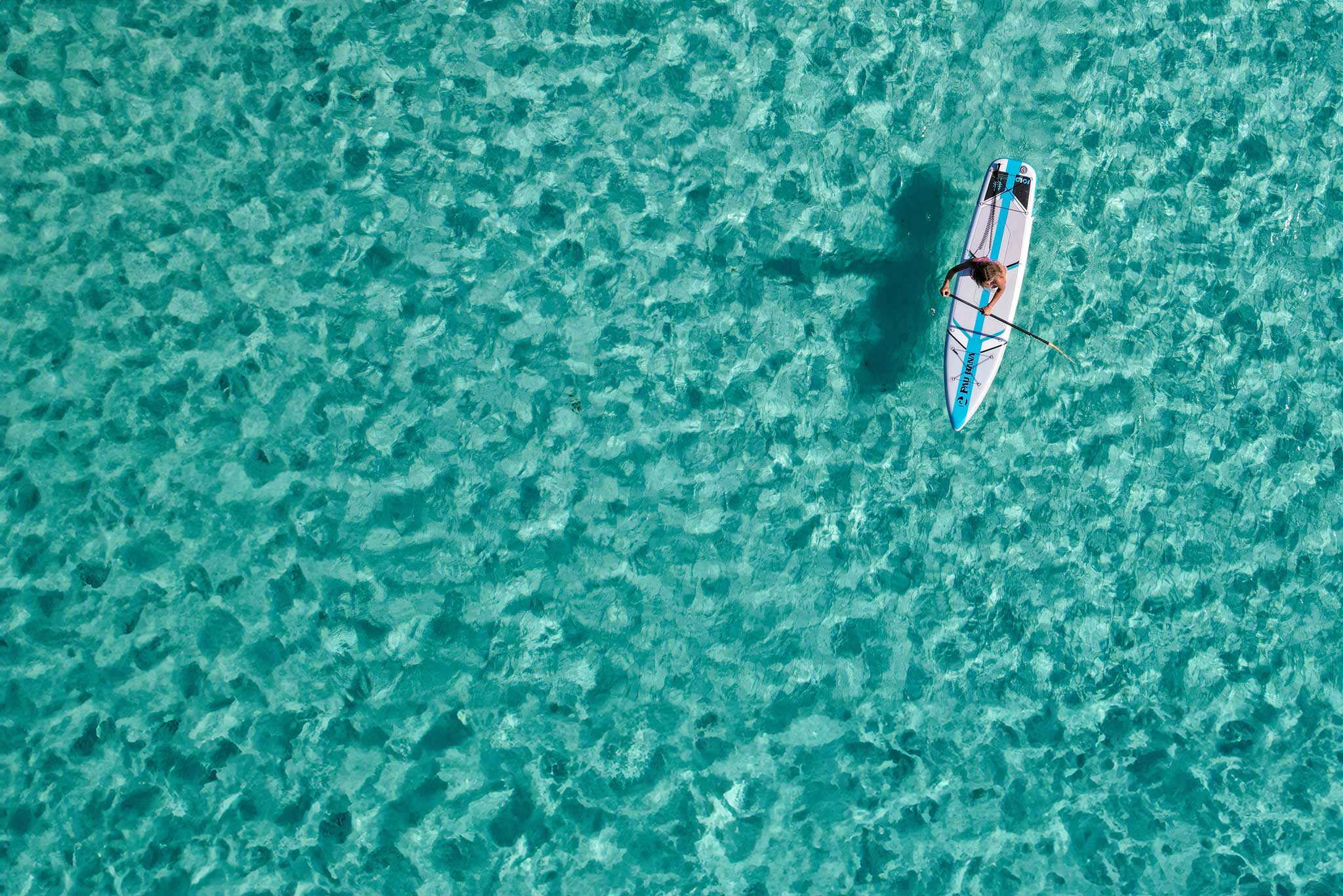 an aerial image of the solo sup backcountry inflatable paddleboard on bright blue water