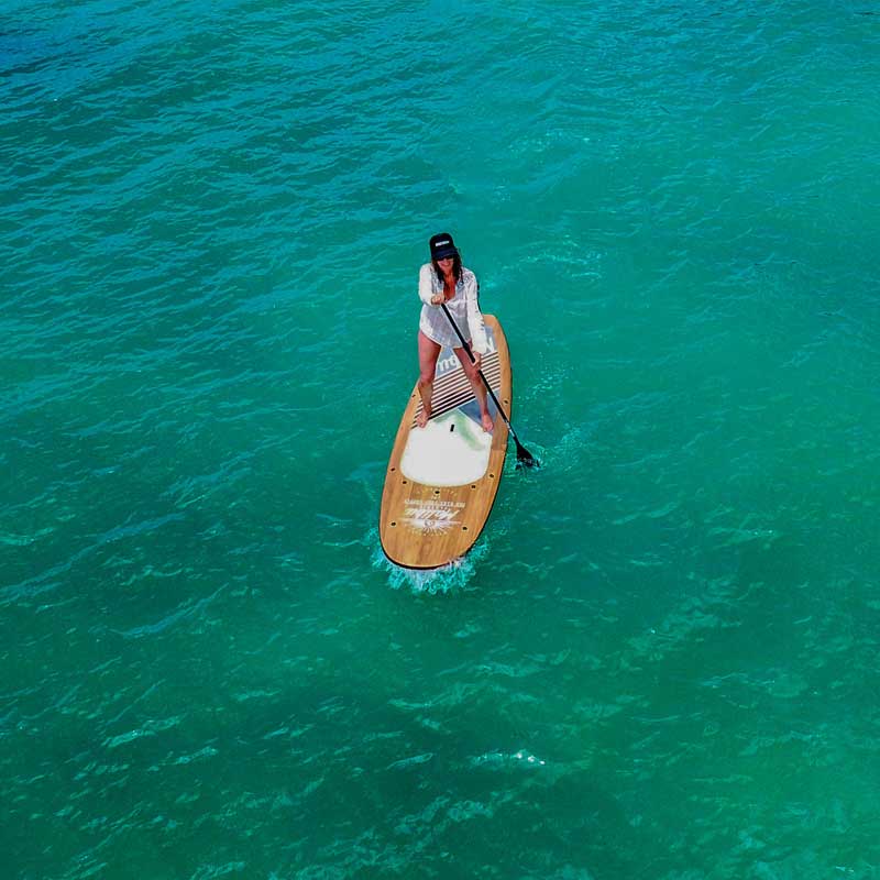 "Pau Hana Surf Supply 10'6" Malibu Classic Wood paddling in turquoise tropical waters Hawaii"