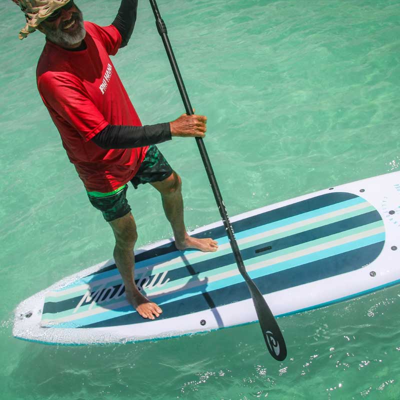 "Pau Hana Surf Supply team member demonstrating the stability of the Malibu Classic SUP board in pristine Hawaiian waters"