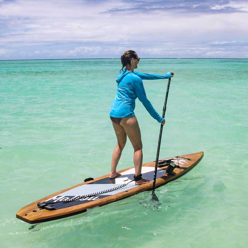 The Pau Hana Surf Supply Malibu Tour touring paddleboard  being paddled on green calm waters in Hawaii wearing a safety leash