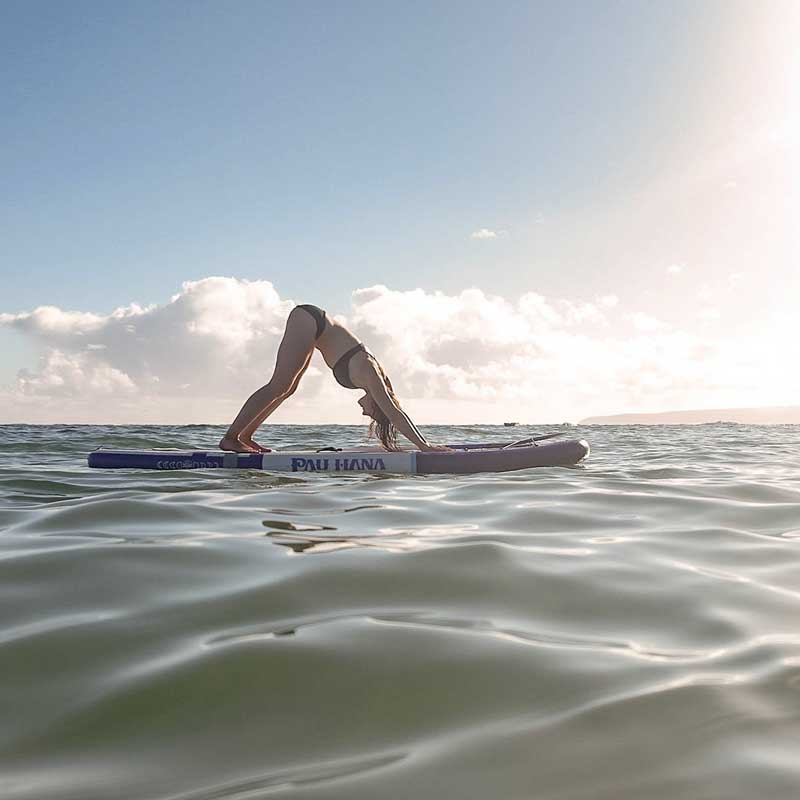 "Pau Hana Surf Supply Moon Mist TPU yoga board action shot - practitioner in downward dog with tropical Hawaiian backdrop"