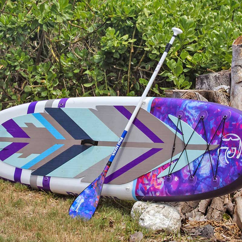 "Pau Hana Surf Supply Moon Mist TPU inflatable SUP with matching cosmic design paddle, showcasing geometric deck pattern and TPU construction"