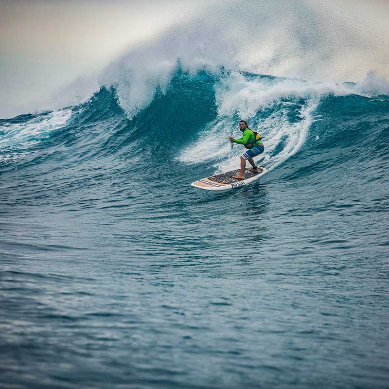 "Paddler riding massive wave on a Pau Hana Surf Supply nose rider the Oahu SUP at Oahu's North Shore"
