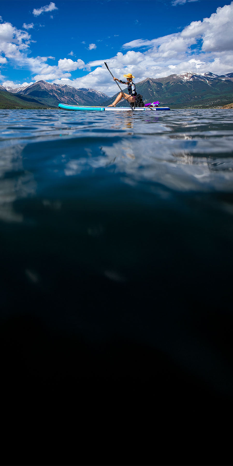 Person paddleboarding on a lake with mountains in the background