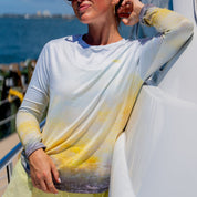 Woman in a colorful shirt and sunglasses standing on a boat with ocean and sky in the background