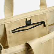 Beige tote bag with a black zipper pocket on a white background
