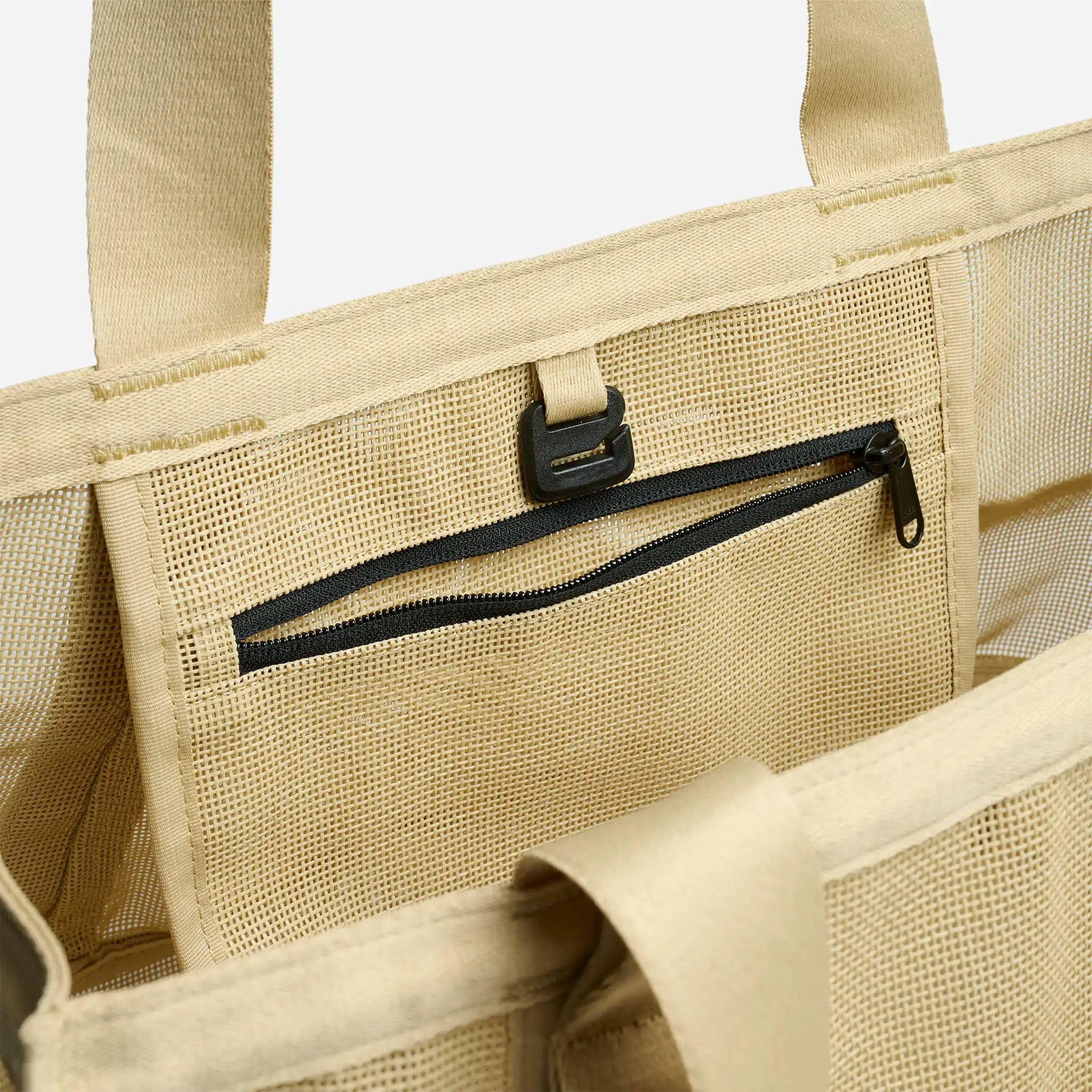 Beige tote bag with a black zipper pocket on a white background