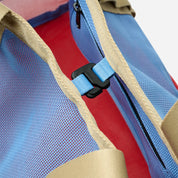 Close-up of a backpack with blue and red interior, beige straps, and black zipper.