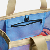 Close-up of a beige tote bag with a blue interior pocket and red lining.