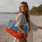 Woman holding a colorful bag on a beach with palm trees in the background