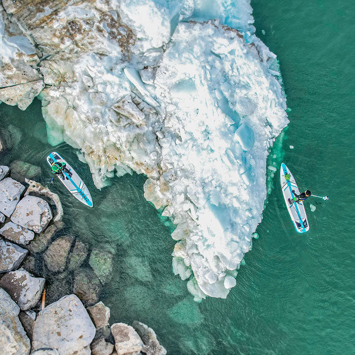 "Pau Hana Surf Supply Solo Backcountry SUPs exploring glacial waters and ice formations during winter alpine paddle expedition"