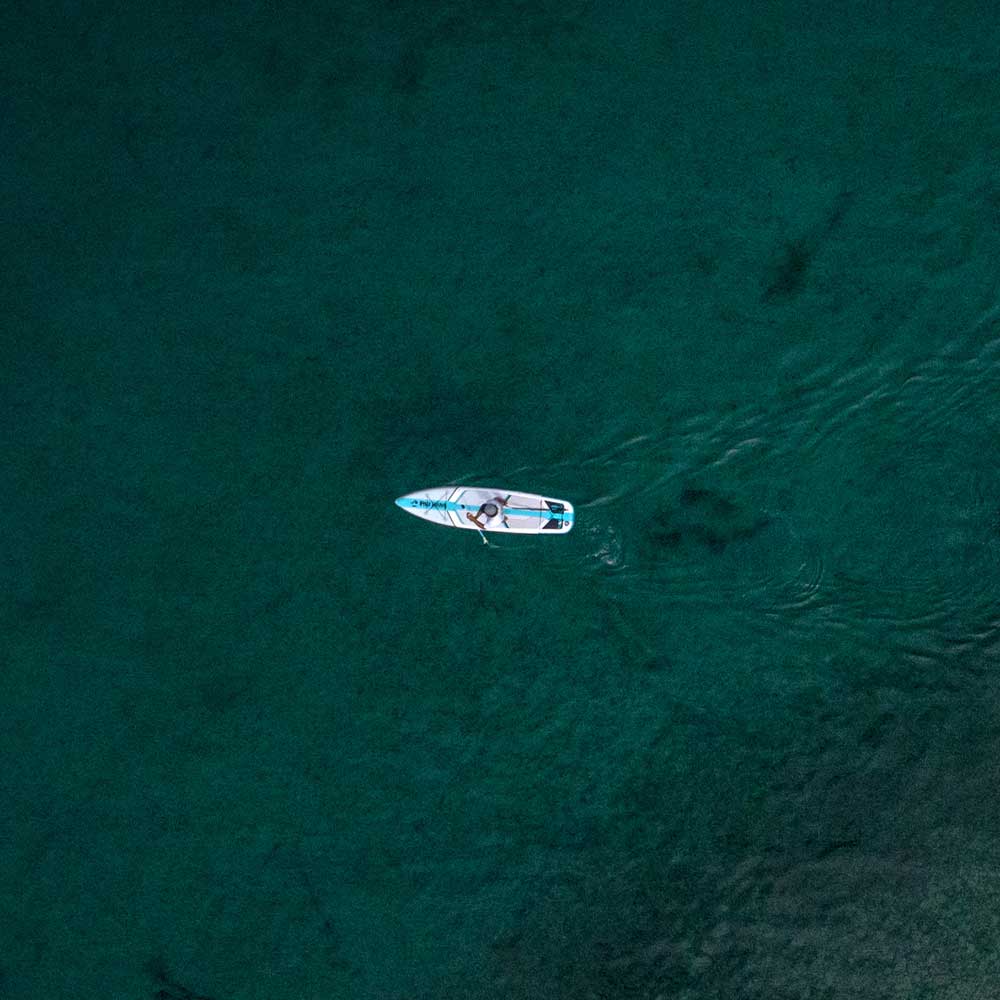 "Aerial drone shot of Pau Hana Surf Supply Solo SUP backcountry board gliding on a lake, showcasing stability and tracking performance"