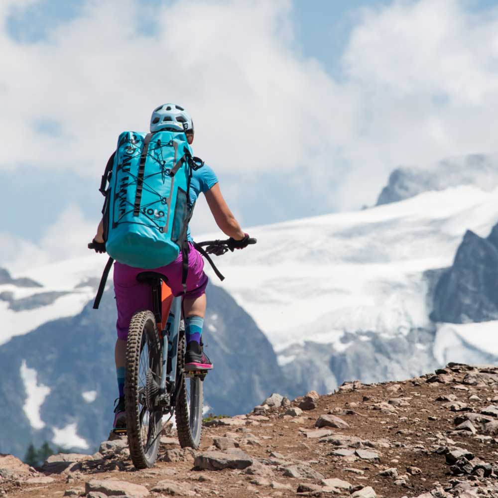 Cycling through the mountains wearing the Pau Hana Surf Supply Solo Sup Backcountry drybag backpack