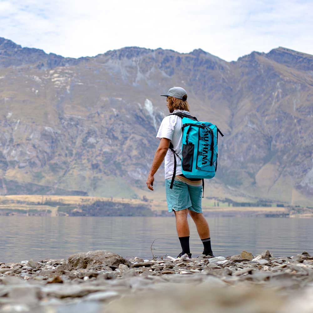 "Hiker wearing the Pau Hana Surf Supply Solo Sup Backcountry travel SUP in hiking backpack for remote lake access"