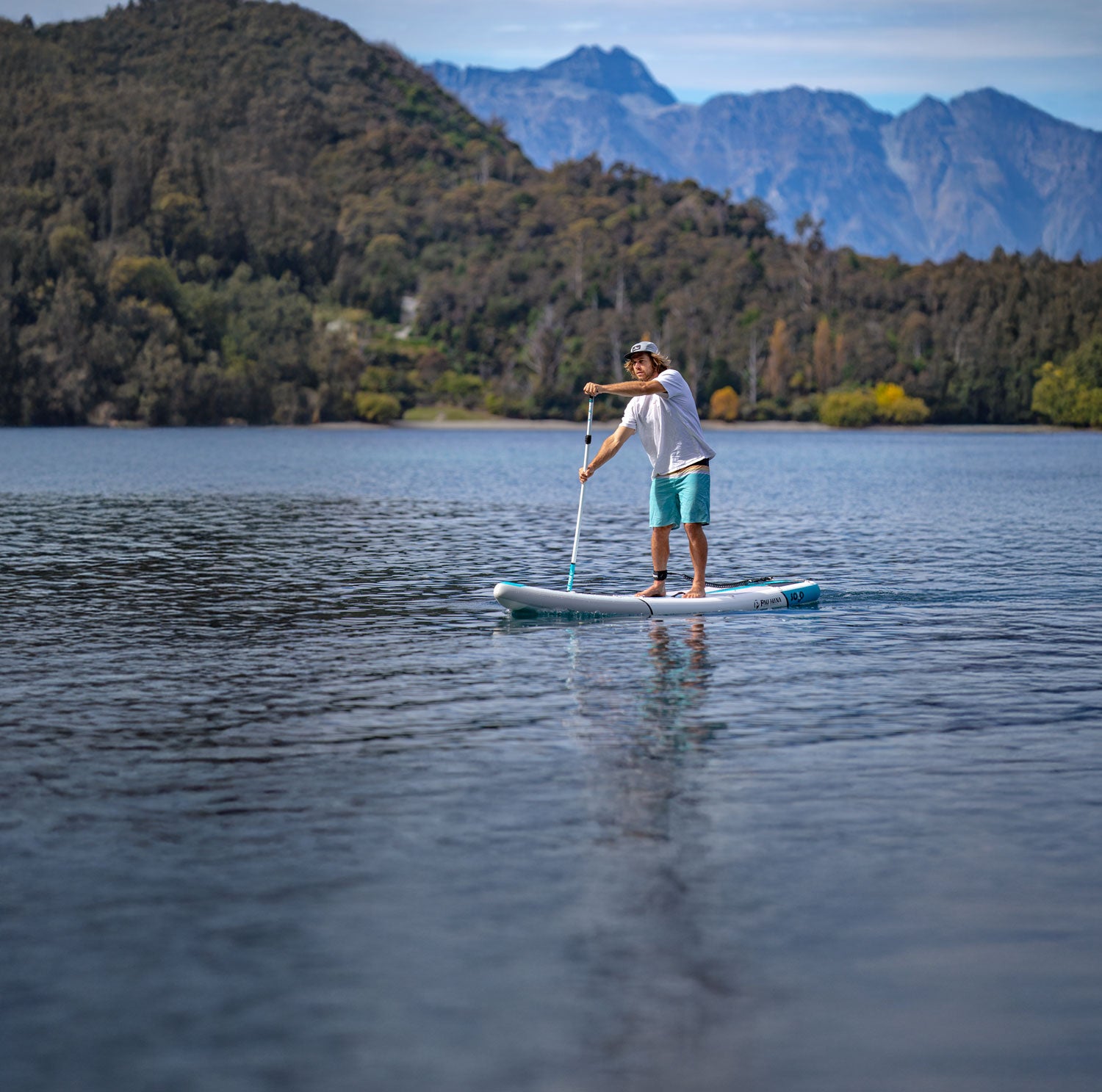 Person paddleboarding on a lake with mountains in the background