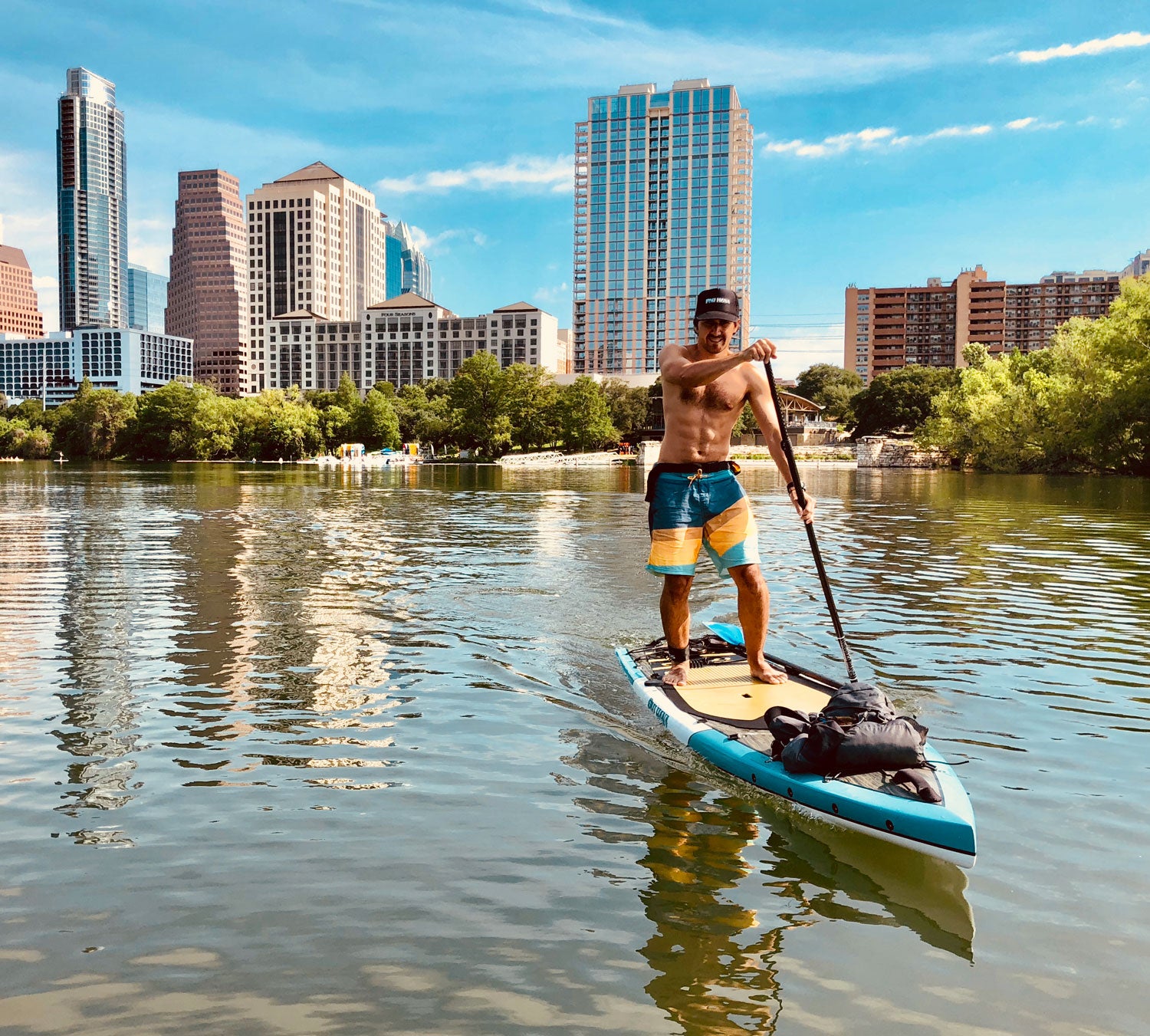 Man paddleboarding on a lake with city skyline in the background